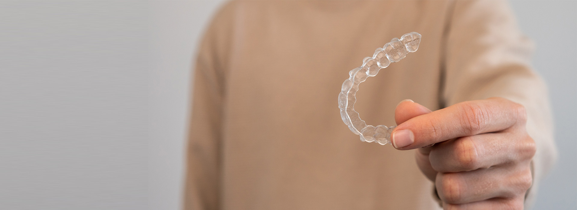 The image shows a person holding a transparent bubble with a hand inside it, against a plain background.